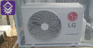 An outdoor LG mini split air conditioner unit enclosed in a protective steel mesh security cage