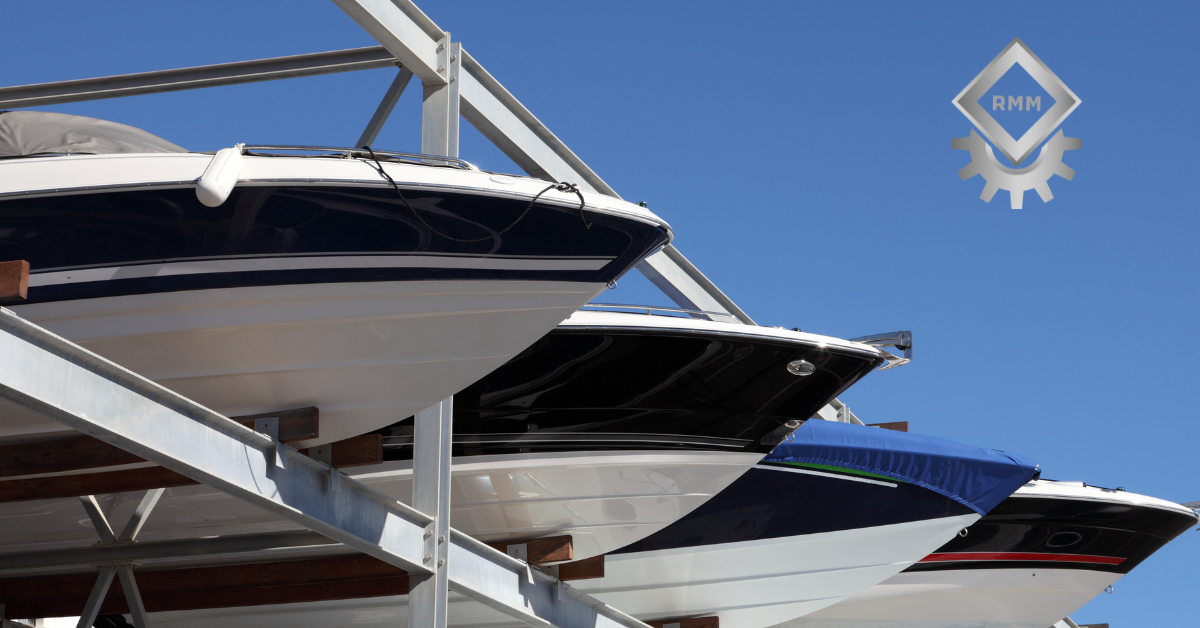 Multiple powerboats stored vertically on a heavy duty galvanized steel marina dry storage rack system under a clear blue sky